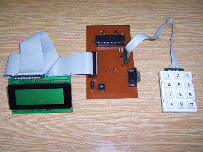 LCD, PIC board and numeric keypad on a wooden desk